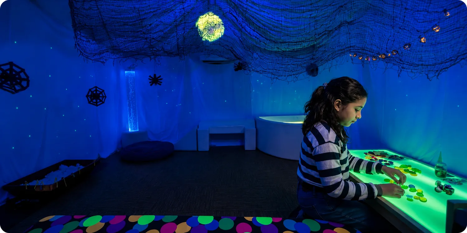 Niña jugando en la mesa de luz dentro de la sala multisensorial