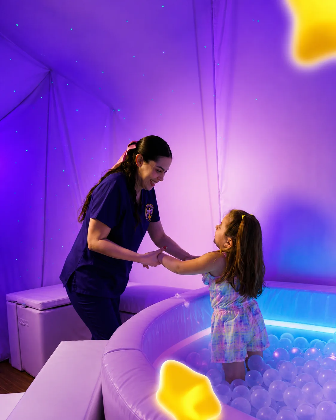Terapeuta y niña jugando en la alberca de pelotas de la sala Snoezelen