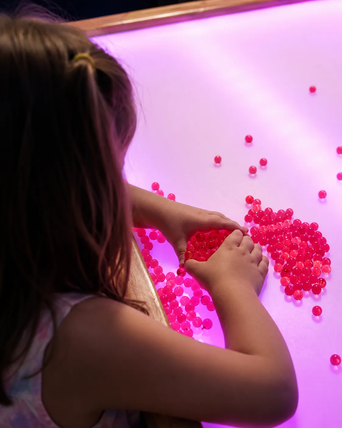 Niña jugando con esferas sensoriales sobre la mesa de luz